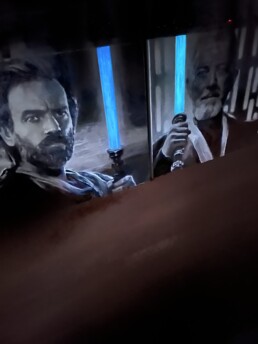Two of the Star Wars trilogy portrait paintings with Ewan McGregor and Alec Guinness holding luminous lightsabers